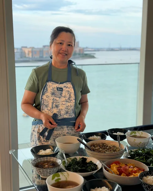 Jenny beside a full table of freshly cooked confinement meals